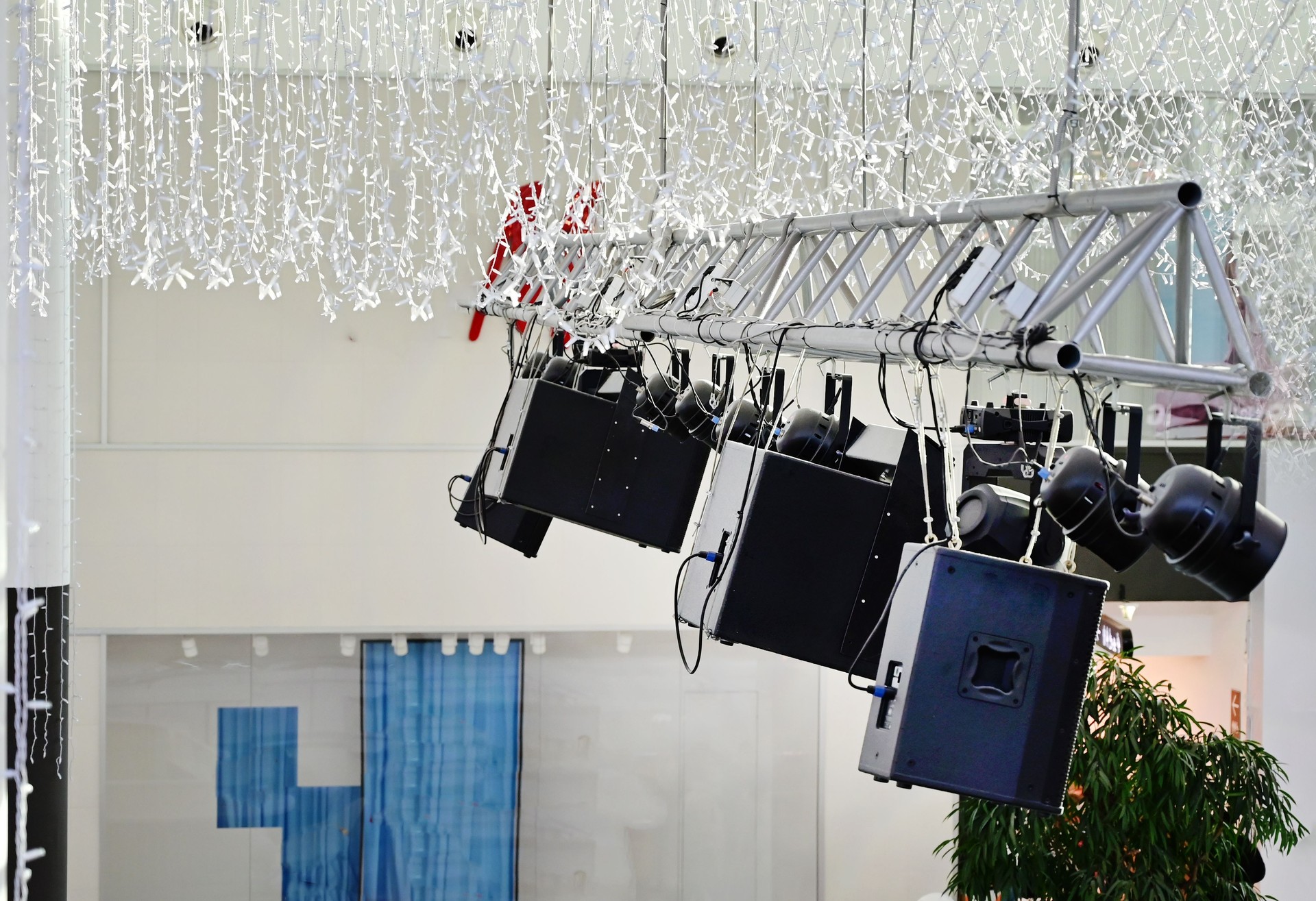 Equipo de audio moderno suspendido de un truss en un espacioso lugar interior durante la configuración de un evento durante el día